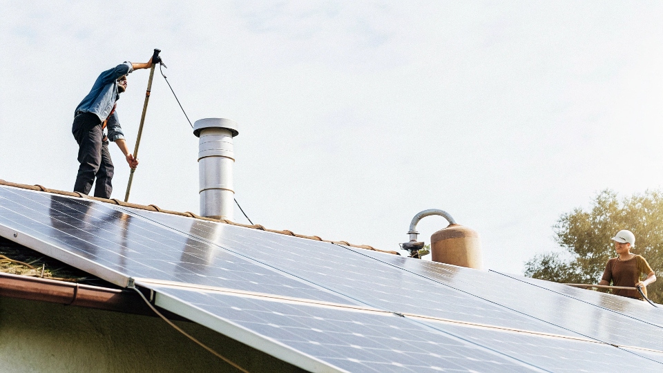 A person cleaning solar panels with a brush and water